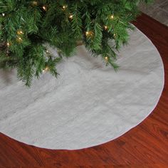 a christmas tree skirt on top of a white tablecloth with lights around the base