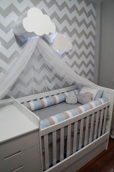 a baby crib in a room with grey and white chevrons on the wall