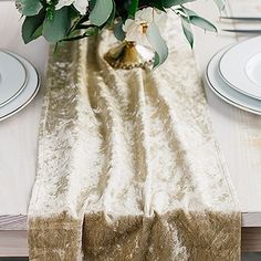 the table is set with white plates and flowers in a vase on top of it