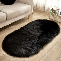 a large black sheepskin rug is on the floor in front of a white couch