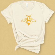 Whether you want to make a statement to save the bees or you simply want a funky insect T- shirt, then this graphic tee is for you. In gorgeously bright cheery yellow, this T-shirt will put a smile on anyone's face. Why not get it as a wearable art gift for her who has everything!DETAILSThis medium weight graphic t-shirt is super soft, comfy. It fits like a well loved favorite tee the first time you put it on, and is soon to become your go to tee. This durable crew neck, short sleeve shirt is ma Bee Graphic, Doodle Flowers, Birds And The Bees, Cut Tees, Save The Bees, Tees For Women, Better Love, Honey Bee, Graphic Shirts