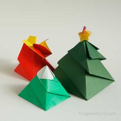 three origami christmas trees with one yellow and one green, on a white surface