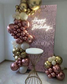 there is a birthday balloon wall with gold and white balloons in the corner next to it