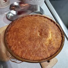 a pie sitting on top of a wooden cutting board next to a bottle of wine