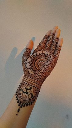 a woman's hand with henna on it, showing the intricate pattern and design