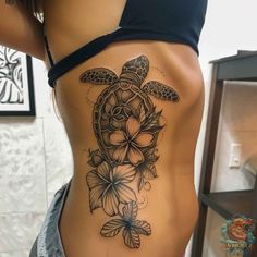 a woman's stomach with a turtle and flowers tattoo on her side ribcage