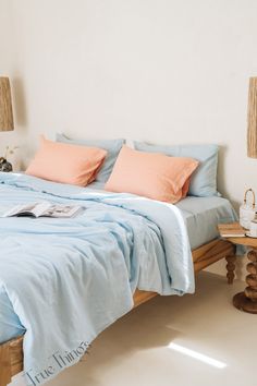 a bed with blue sheets and orange pillows