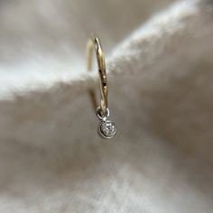 These is a  super delicate 1mm wide sleeper huggie style hoop in solid 9ct yellow gold. It has a subtle hammered texture which really catches the light.  Hanging below the hoop is a 2mm natural genuine bright white diamond charm made in solid platinum.  These hoops are great if you want a subtle look when worn alone and they also stack so well in a curated ear look.  If you require more of this item than is showing as available to purchase please send me a message and I can advise on if I have more available.  All of my items are handmade by myself in my workshop in Surrey, England.  They come well packaged in a branded gift box and would make a lovely gift.  If you like one of my designs but would rather it in a different metal or gemstone please send me a message as I may well be able to Yellow Gold Huggie Jewelry With Single Diamond, Stackable Yellow Gold Huggie Earrings In Sterling Silver, Yellow Gold Stackable Huggie Earrings In Sterling Silver, 14k Gold Hoop Earrings With Single Diamond, Yellow Gold Sterling Silver Stackable Huggie Earrings, White Gold Recycled Jewelry With Single Diamond, White Gold Jewelry With Single Diamond In Recycled Gold, Single Diamond White Gold Jewelry In Recycled Gold, White Gold Single Diamond Jewelry In Recycled Gold