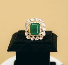 an emerald and diamond ring sitting on top of a black box