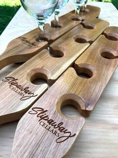 wooden cutting boards with wine glasses on them sitting on top of a table in the grass