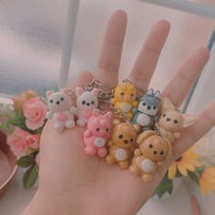 a person holding several small animal key chains in their hand, with flowers behind them