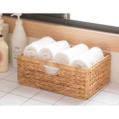 towels are in a basket on the bathroom counter next to soap and lotion bottles