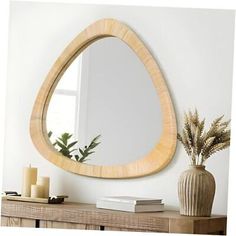 a mirror sitting on top of a wooden table next to a vase