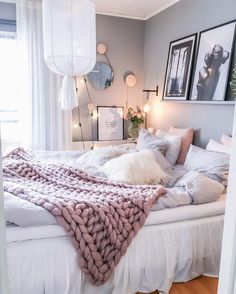 a white bed topped with pillows and blankets next to two framed pictures on the wall