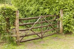 an old wooden gate surrounded by greenery