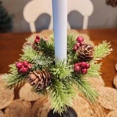 a candle with pine cones and berries on it sitting in front of some crackers