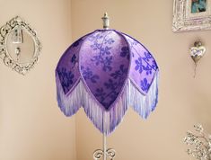 a purple lamp shade on a table in a room with pictures and other decorations around it