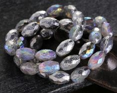 a close up of a bunch of glass beads on a table next to a piece of wood