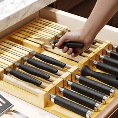 a person is reaching for knives in a drawer