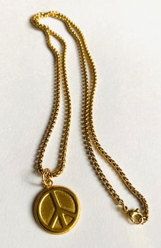 Long Peace Necklace Plated brass. Sturdy coin size charm of brass. Peace sign design. Sturdy long 22" gold over steel chain. Steel lobster clasp. Super fun to wear and layer with other necklaces. Long Peace Necklace Brass Round Pendant Charm Necklace, Yellow Gold Brass Medallion Charm Necklace, Yellow Gold Coin Charm Necklace With Adjustable Chain, Vintage Gold-plated Tarnish-resistant Charm Necklaces, Vintage Gold Plated Tarnish Resistant Charm Necklace, Vintage Gold-plated Tarnish-resistant Charm Necklace, Gold Medallion Charm Necklaces For Everyday, Gold Medallion Charm Necklace For Everyday, Brass Coin Charm Necklace Tarnish Resistant