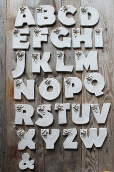 the letters and numbers are made out of white ceramic tiles on a wooden background with an animal paw print