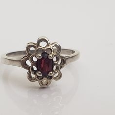 Dainty silver ring with flower shape. Double layer of open framed petals with central prong set glass simulated garnet oval gem. Marked 925 and CA.  Size US 5 3/4.  Previously owned and in good condition. There are minor signs of age/use to the band. The pictures are part of the description.  Do browse our other items. We combine shipping for savings. International purchasers can contact the shop for a quote to the shipping address. Vintage Oval Garnet Birthstone Ring, Vintage Oval Flower Ring Hallmarked, Vintage Oval Hallmarked Flower Ring, Vintage Style Oval Flower Ring For Formal Occasions, Vintage Oval Flower Ring For Formal Occasions, Silver Oval Hallmarked Flower Ring, Silver Oval Flower Ring Hallmarked, Hallmarked Silver Oval Flower Ring, Classic Oval Hallmarked Flower Ring