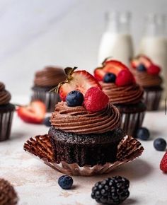 cupcakes with chocolate frosting and fresh berries on the top are ready to be eaten