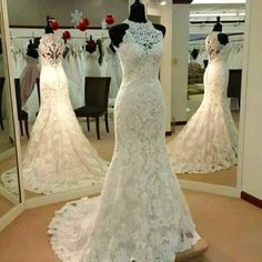 a white wedding dress on display in front of a mirror with other dresses behind it