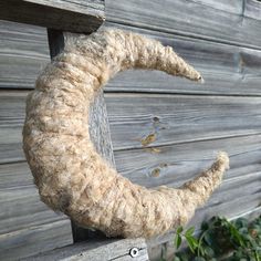 a close up of a piece of wool hanging on a wooden fence near a bush