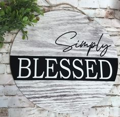 a wooden sign that says simply blessing on the side of a brick wall next to a potted plant