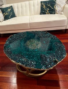 a glass table sitting on top of a hard wood floor next to a white couch