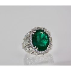 This is part of Chairish’s Fine Jewelry assortment.  Oval Emerald 12.25 Carat Diamond Surround 8.85 Carat Total Weight 21.10 Carat  This oval Emerald weights in at 12.25 carats and is a gorgeous Emerald Green with transparency. The Diamonds weigh in at 8.85 Carats and the mount is exceptional the Diamonds are VS1-VS2 and G-J in color. This is a bombe mount. The shoulders of the ring are embellished with baguette cut Diamonds in the center border with a perimeter of round cut Diamonds accents. Th Luxury Marquise Emerald Ring, Exquisite Oval Emerald Ring In Platinum, Luxury Oval Emerald Ring With Brilliant Cut, Platinum Oval Emerald Ring With 17 Jewels, Oval Platinum Emerald Ring With 17 Jewels, Luxury Oval Emerald Ring With Prong Setting, Gia Certified Oval Emerald And Diamond Ring, Oval Platinum Halo Ring For Formal Occasions, Luxury Platinum Emerald Ring With Halo Setting