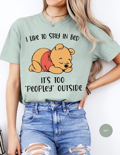 Wrap yourself in the warmth of relaxation with our "Cozy Hibernation Retreat Tee." This delightful shirt features Winnie the Pooh in his favorite spot, snug in bed, declaring, "I like to stay in bed. It's too peoply outside." Embrace the comfort of solitude and let the world outside fade away as you enjoy the tranquility of your own cozy sanctuary. Comfortable Crew Neck Bedtime Tops, Comfortable Crew Neck Top For Bedtime, Cute Tops For Lounging, Casual Letter Print Top For Bedtime, Comfortable Crew Neck T-shirt For Lounging, Bedtime Letter Print Crew Neck Tops, Cozy Crew Neck T-shirt For Loungewear, Cozy Winter T-shirt For Loungewear, Casual Crew Neck T-shirt For Bedtime