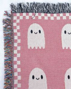 a pink and white rug with three ghost faces on it, one has black eyes