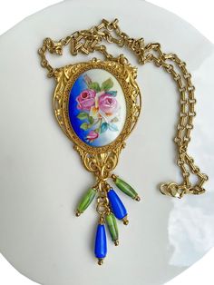 "Such a gorgeous romantic necklace! This beauty starts with a vintage rollo chain with a lobster claw clasp.  The chain is 24\" in length.  From that hangs a bold pendant.  The pendant consists of a vintage hand painted pin that has been repurposed onto this necklace.  The painting is on ceramic and set in an intricate gold tone setting.   This vintage pin has been hand wired to a large brass filigree stamping. I have added another of the same stamping to the back to cover up the hand wiring and Heirloom Blue Necklaces For Weddings, Antique Blue Necklaces With Vintage Charm, Antique Blue Necklace With Vintage Charm, Vintage Blue Pendant Necklace, Handmade Victorian Blue Necklaces, Handmade Victorian Blue Necklace, Altered Art Jewelry, Art Nouveau Pendant, Romantic Necklace