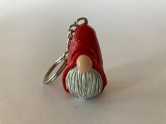 a red keychain with a gnome's head on it is sitting on a white surface