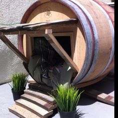 a wooden barrel sitting on top of a cement floor next to potted planters