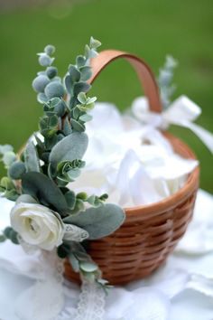 a basket filled with flowers and greenery sitting on top of a white table cloth