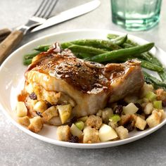 a white plate topped with meat, potatoes and green beans next to a glass of water