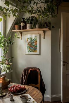 a dining room table with plates and bowls on it, next to a potted plant