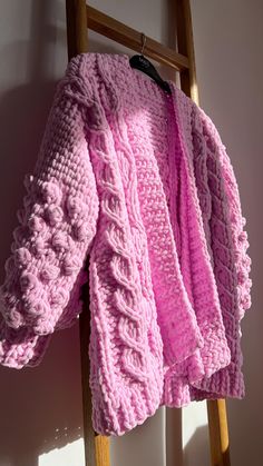 a pink knitted sweater hanging on a ladder