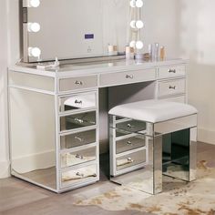 a white vanity with lights on it and a stool in front of the counter top