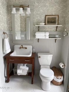 a white toilet sitting next to a sink in a bathroom under a mirror and lights