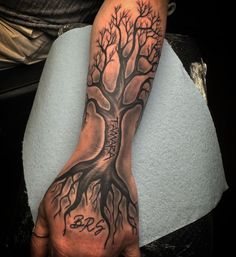 a man's hand with a tree tattoo on it