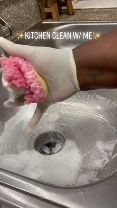 a person washing their hands in a kitchen sink with soap and sponges on it