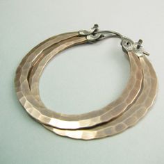 "The ultimate large bronze and sterling silver hoop earrings. Our new bronze ( also known as red brass and nugold ) Rio design, meticulously and deftly forged for a polished but rustic look. Finished with our sterling silver latch design for a secure and easy to use closure that maintains a sleek profile. A dynamic pair of handmade hammered hoops that are sure to become a favorite addition to your jewelry collection. Oxidized, brushed and polished to finish. Rio Hoops are a signature Mocahete de Rose Gold Brass Hoop Earrings With Ear Wire, Rose Gold Hoop Earrings With Brass, Small Rose Gold Brass Hoop Earrings, Small Bronze Metal Hoop Earrings, Artisan Electroformed Hoop Earrings, Handmade Bronze Hoop Jewelry, Hammered Rose Gold Sterling Silver Hoop Earrings, Rose Gold Hammered Sterling Silver Hoop Earrings, Rose Gold Hammered Small Hoop Earrings