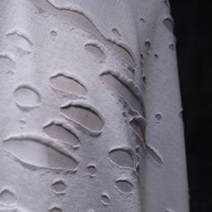 the fabric is white and has drops of water on it's side, as well as small holes in the fabric