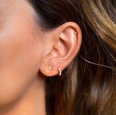 a close up of a woman's ear with two gold piercings on it