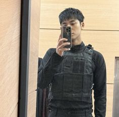 a young man taking a selfie in front of a mirror with his cell phone