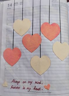 paper hearts hanging from strings on a piece of lined paper with words written in them